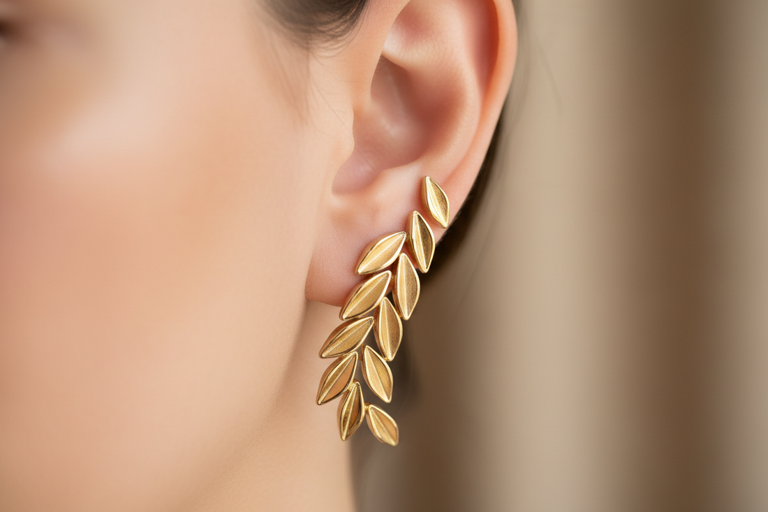pendiente trepador dorado con motivos de hojas que sube por el lóbulo