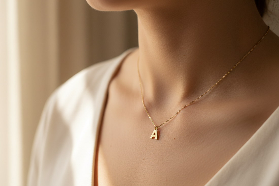 cuello de una mujer luciendo una cadena fina dorada con la letra inicial de su nombre colgando